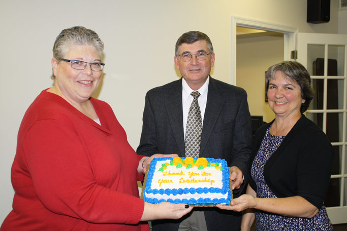 Board chair Phyllis Miller (left) presents a cake to Loren and Earlene Horst, thanking them for their long service to Virginia Mennonite Missions.